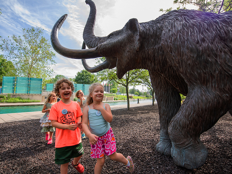 Kids standing with mastodons