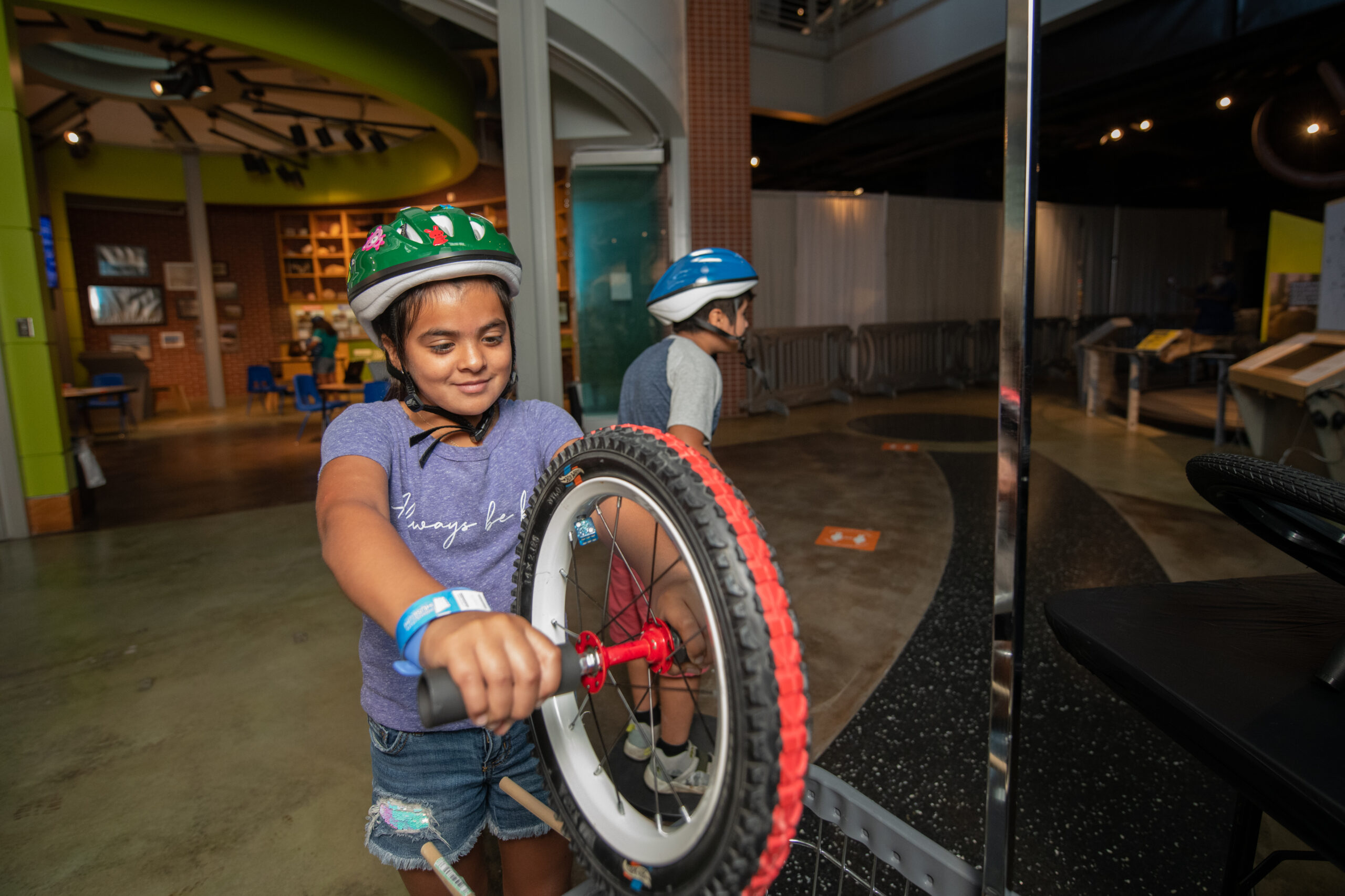Child wearing helmet and playing with bicycle wheel