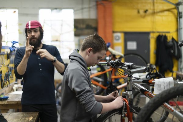 Child in gray hoodie fixing bike gears