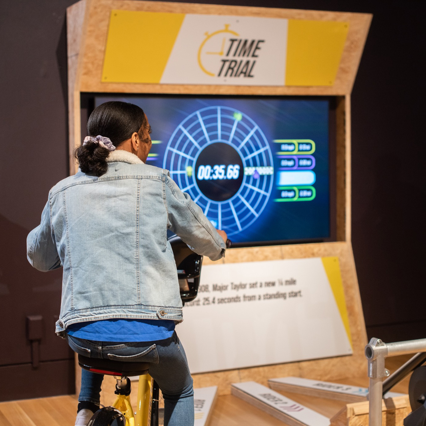 Person in denim jacket sitting on stationary bike