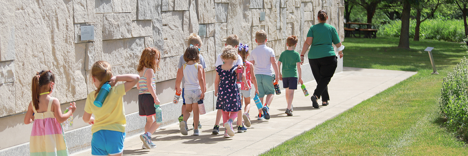 Children walking in line on outdoor sidewalk