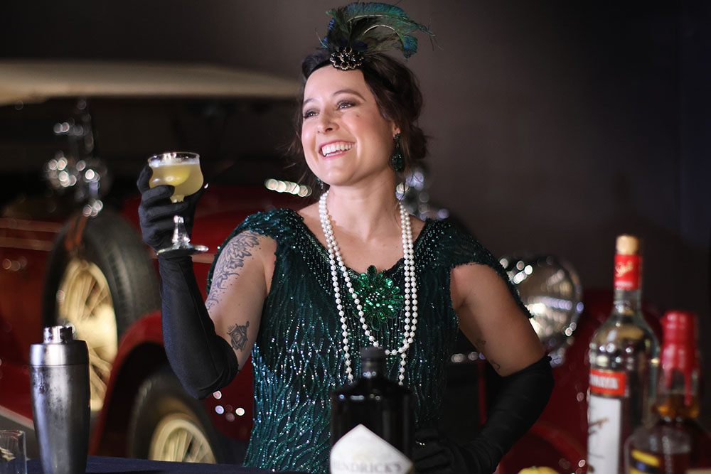Woman dressed up in green glittery flapper costume, holding cocktail