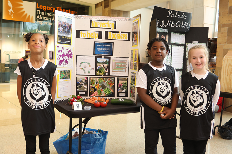 students standing in front of eco-science fair presentation