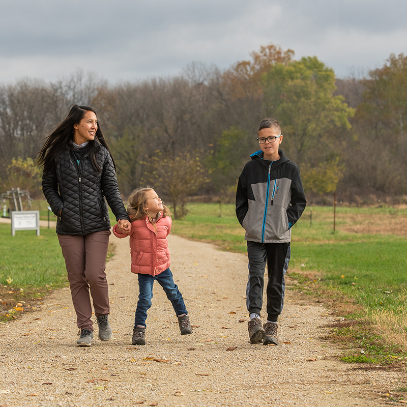 mother and two children walking on dirt trail