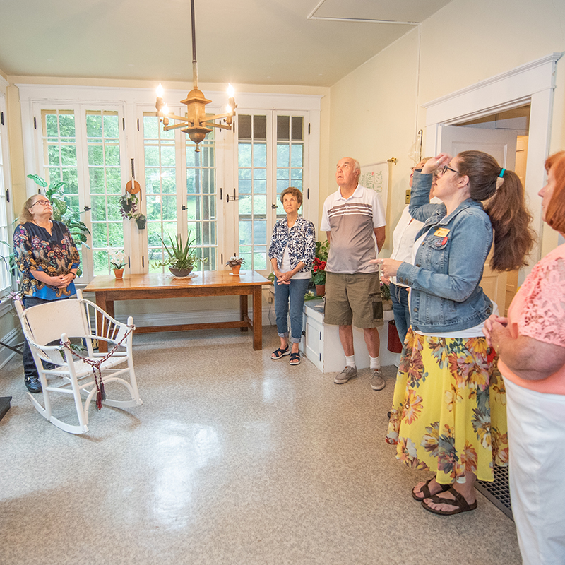 group of people standing in a room of a historic house looking at chandalier